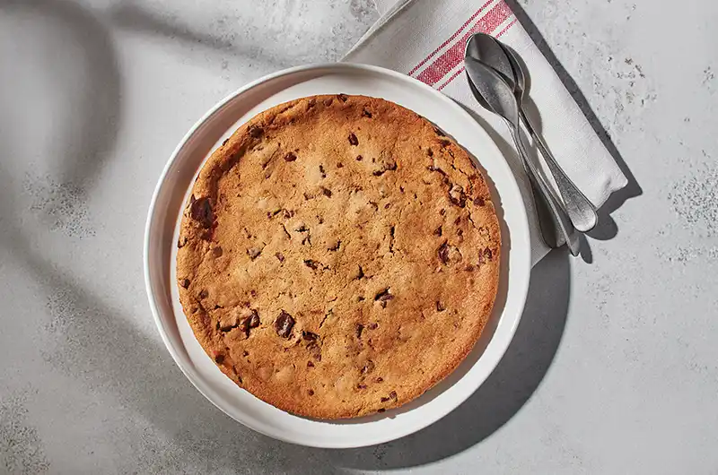 Biscuit géant avec énorme biscuit chaud aux pépites de chocolat, le tout accompagné d’un riche coulis au chocolat