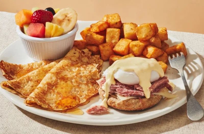 Béné classique avec un œuf poché servi sur muffin anglais avec jambon effiloché, fromage mozzarella et sauce hollandaise. Servi avec un choix