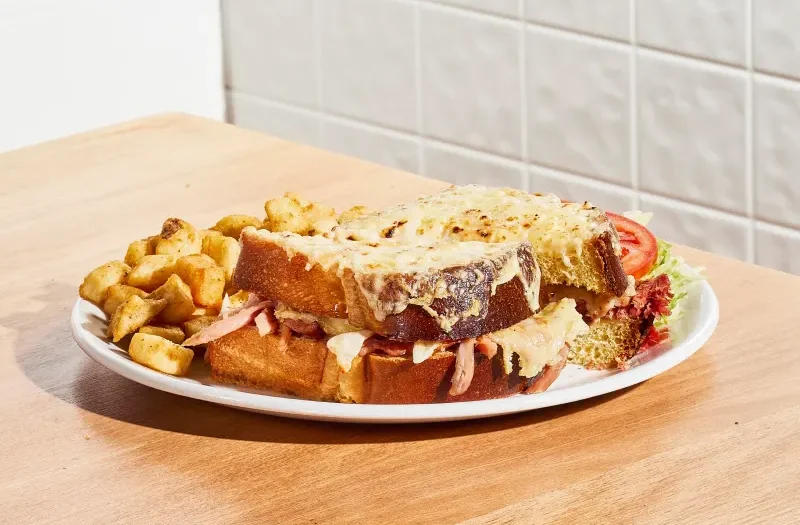 Croque monsieur jambon & fromage avec jambon effiloché, fromage mozzarella et fromage Cantonnier dans un pain aux oeufs gratiné avec de la sauce