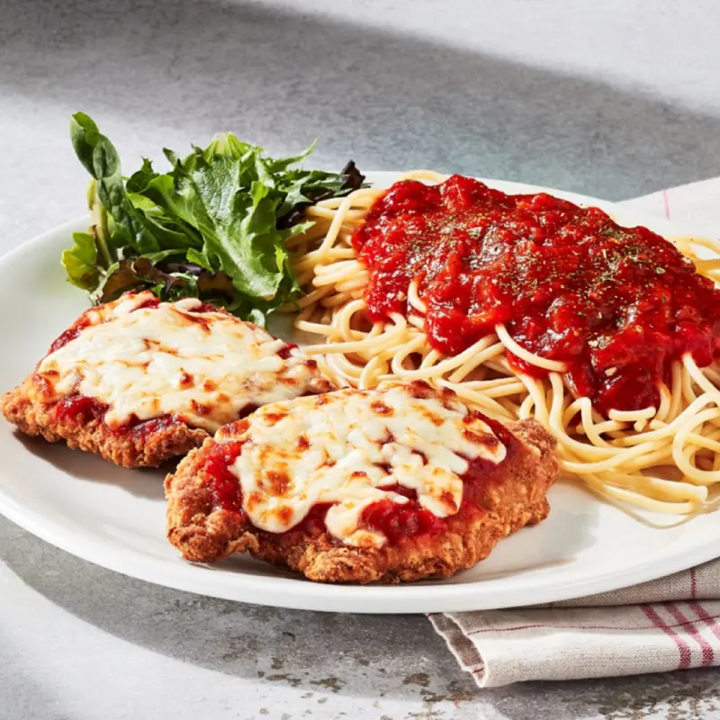 Poulet parmigiana avec deux tendres morceaux de poulet panés nappés de sauce napolitaine, le tout servi gratiné avec un accompagnement au choix