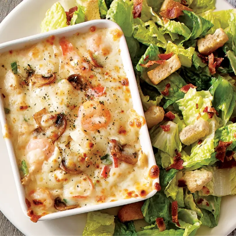 Casserole de fruits de mer avec mélange de la mer, champignons et oignons verts dans une sauce crémeuse, le tout servi gratiné avec un
