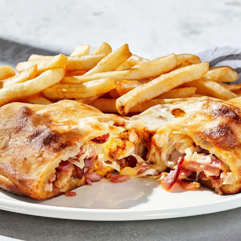 Pizza Panzerotti au bacon avec chausson de pâte à pizza farci de bacon, fromage à pizza mozzarella, oignons, sauce au fromage et sauce BBQ. Le