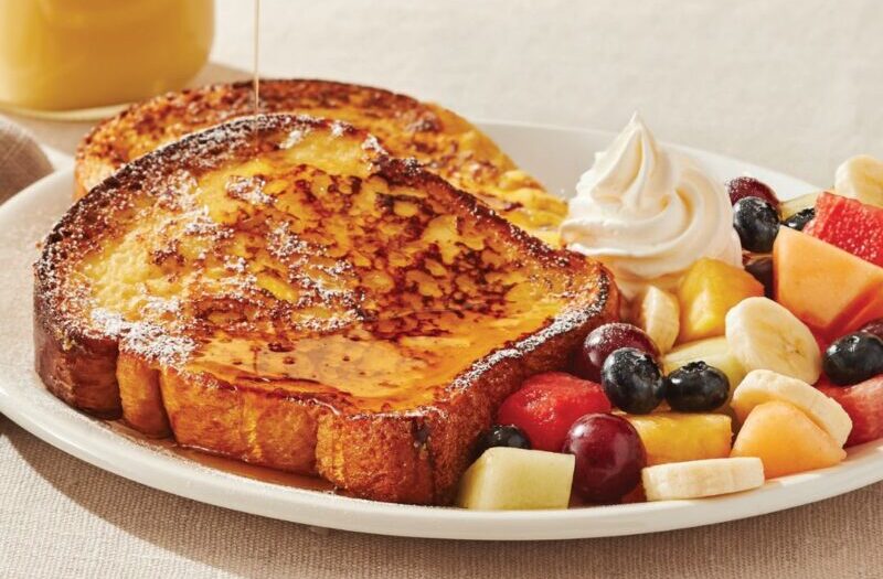 French Toast with two slices of French egg toast topped with whipped cream and powdered sugar