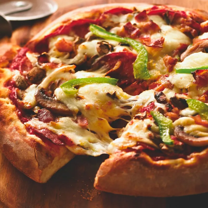 International pizza with signature pizza sauce, pepperoni, capicollo, bacon, mushrooms, green bell peppers, onions, and mozzarella pizza cheese