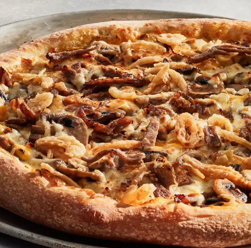 Philly, Cheese sauce, Philly steak, roasted mushrooms, sautéed onions, mozzarella pizza cheese, and crispy onions