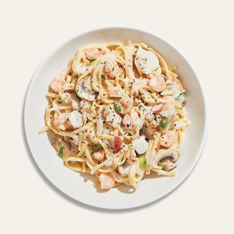 Seafood linguine with creamy seafood sauce with seafood mix, roasted mushrooms, and green onions