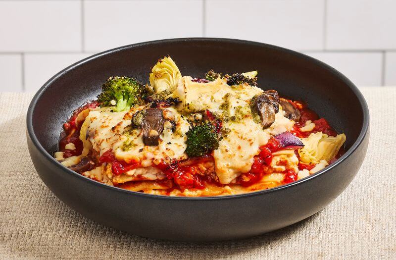 Chicken, Pesto & Brie Lasagna with neapolitan sauce, ricotta, chicken breast strips or plant-based chicken, red bell peppers, broccoli